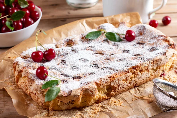 Sponge cake with cherries on a wooden table, selective focus. Homemade cake