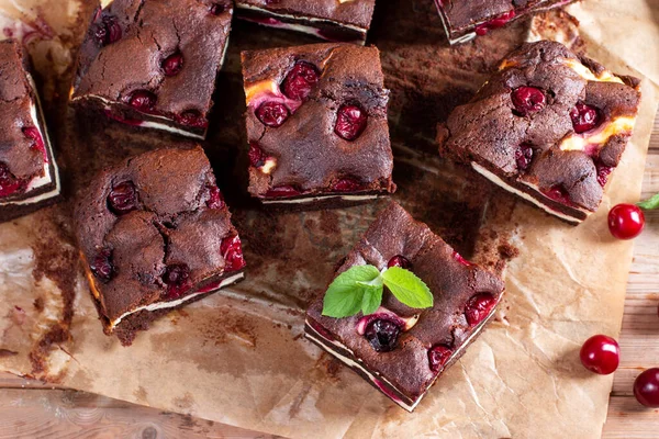 Tasty chocolate brownie with cherry. Pieces of cake on rustic wooden table