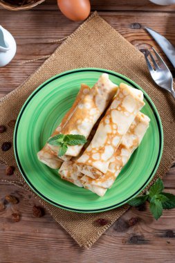 Sweet pancake with cottage cheese and raisins on rustic wooden table. Pancakes with cheese. Shrovetide.