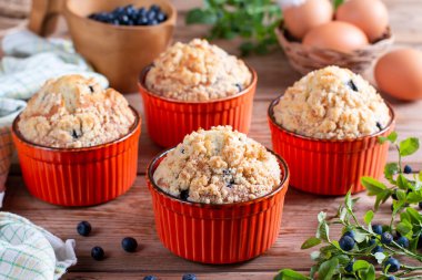 Blueberry muffins baked with fresh blueberries on rustic wooden table with fresh mint
