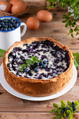 Pie with fresh and cooked blueberries on rustic wooden table