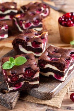 Brownie with cottage cheese and cherries on rustic wooden table