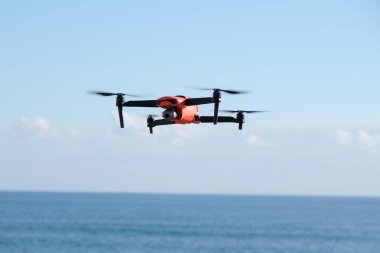 Deniz ve gökyüzü arka planında uçan dron.