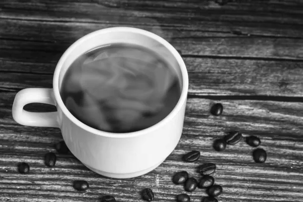 木製のテーブルの上には ホットアロマコーヒーと散乱コーヒー豆のカップ 爽やかな朝のドリンク — ストック写真