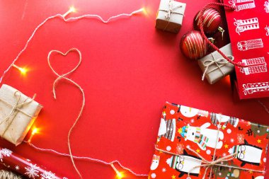 Parlak kırmızı arka planda Kraft kağıdının içinde hediye olarak sunulan Noel kompozisyonu. Düz plan, üst görünüm, üst görünüm, düz görünüm, üst görünüm, kopyalama alanı. Noel, kış, yeni yıl konsepti. Metin için boşluk