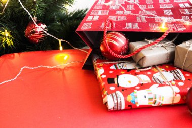 Parlak kırmızı arka planda Kraft kağıdının içinde hediye olarak sunulan Noel kompozisyonu. Düz plan, üst görünüm, üst görünüm, düz görünüm, üst görünüm, kopyalama alanı. Noel, kış, yeni yıl konsepti. Metin için boşluk