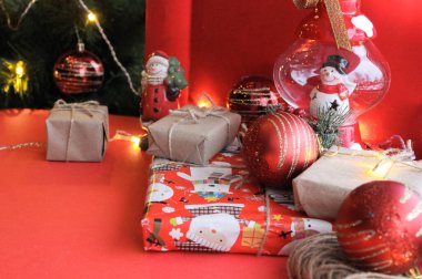 Parlak kırmızı arka planda Kraft kağıdının içinde hediye olarak sunulan Noel kompozisyonu. Düz plan, üst görünüm, üst görünüm, düz görünüm, üst görünüm, kopyalama alanı. Noel, kış, yeni yıl konsepti. Metin için boşluk