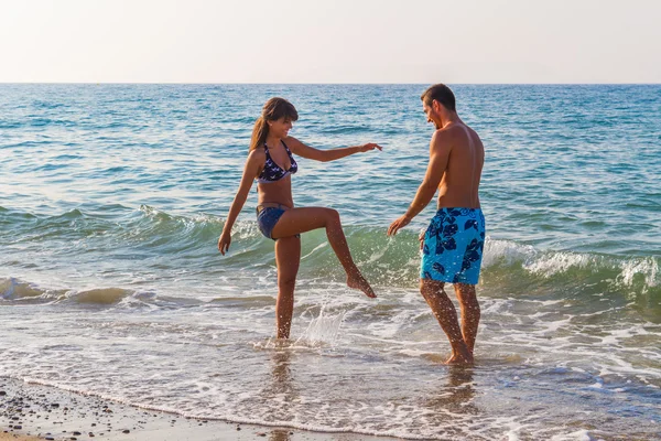 Jovem casal provocando uns aos outros na praia — Fotografia de Stock