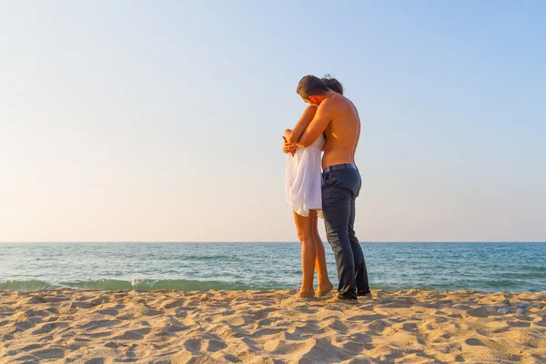 Ungt par tätt omfamnade på stranden — Stockfoto