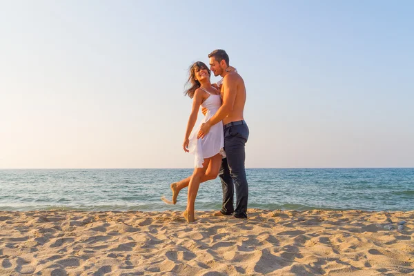 Jonge paar plagen elkaar op het strand — Stockfoto