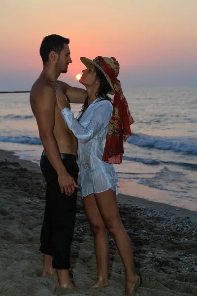 Feliz joven pareja tiernamente abrazando y besándose en la playa al atardecer . —  Fotos de Stock