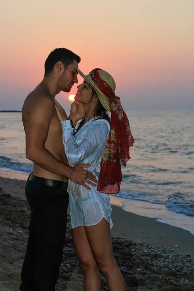 mutlu şefkatle kucaklayan ve gün batımında sahilde öpüşme genç Çift.