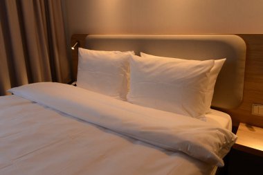 Lüks modern otel odası, insan yok, rahat sıcak renkli yastıklar, halılar, perdeler, döşemeler ve mobilyalar. Seyahat tatili rahatlama kavramı.