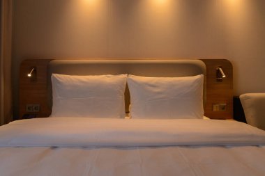 Lüks modern otel odası, insan yok, rahat sıcak renkli yastıklar, halılar, perdeler, döşemeler ve mobilyalar. Seyahat tatili rahatlama kavramı.