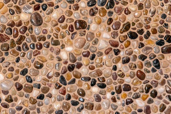 Round gravel pebble stone wall decoration. Beige warm pebble stone tecture background