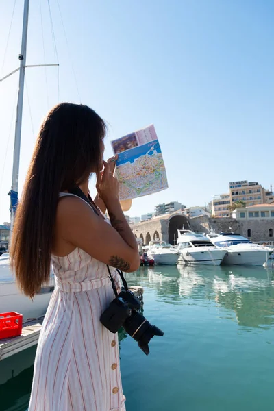 Elegante joven visitante turística que camina en un recorrido turístico en el puerto veneciano de Heraklion, Creta, Grecia. Astilleros venecianos en segundo plano — Foto de Stock