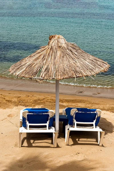 Plage vide avec chaises longues, chaises longues, parasols en paille et ciel bleu. Destination de vacances d'été en Méditerranée, Héraklion, Crète, Grèce. — Photo