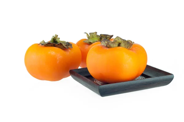 Three persimmon on wood plate and white background — Stock Photo, Image