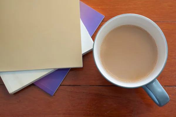 Koffie beker en stack boek over rode hout patroon — Stockfoto