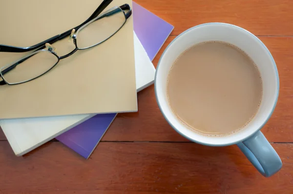 Tazza di caffè e stack book bicchieri su tavolo di legno rosso — Foto Stock