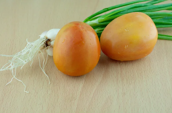 Tomate fresco e cebola de primavera em fundo de madeira — Fotografia de Stock