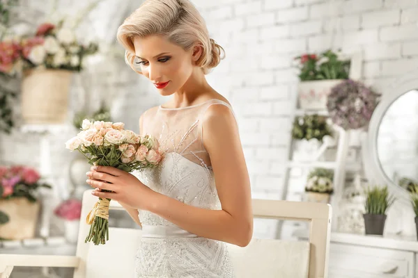 Die schöne Frau posiert im Hochzeitskleid Stockfoto