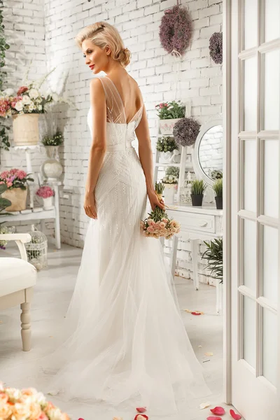 Die schöne Frau posiert im Hochzeitskleid lizenzfreie Stockbilder