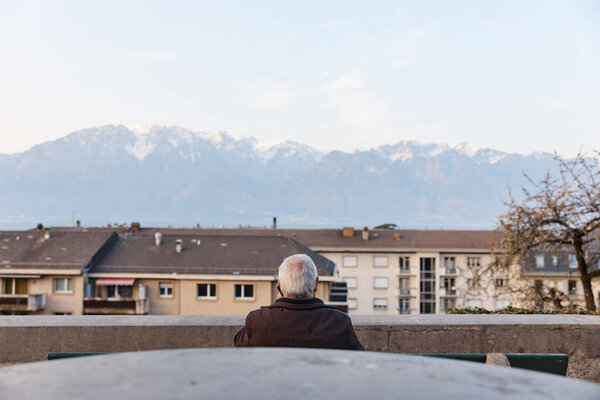 Senior man talking on phone on background of Alps in Switzerland. Rear angle. Royalty Free Stock Images