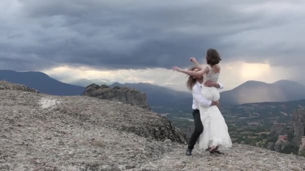 Adam kalkar ve dağlarda kucaklar kızı — Stok video
