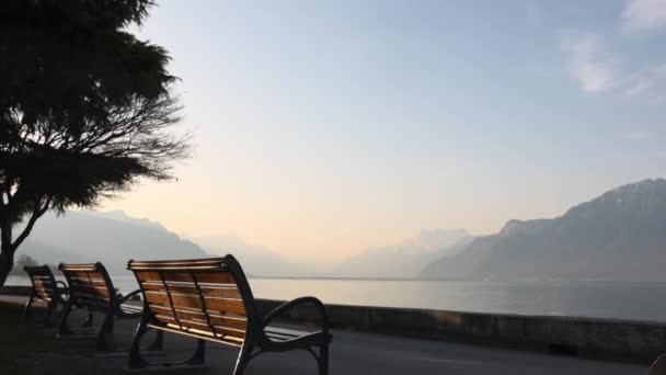 Bänkar och väg på Genèvesjöns strand med Alperna — Stockvideo