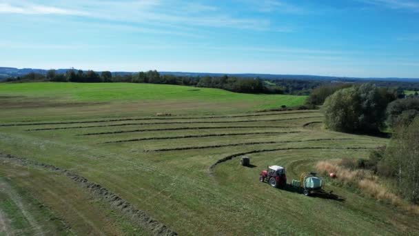 畑のトラクターは、切断された干し草をベール、空中ビューに収集します。ベールマシンはフィールドでわらを収集し、俵を作る. — ストック動画