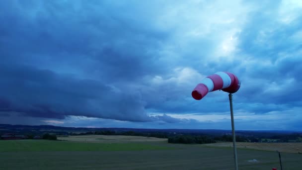 Chaussette de vent de l'aéroport rouge-blanc est soufflé par le vent contre un ciel orageux. — Video