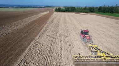 Büyük bir traktörle büyük bir tarlayı yaralamak. Kış mahsulü ekmeden önce toprak ekimi. Yukarıdan görüntüle.