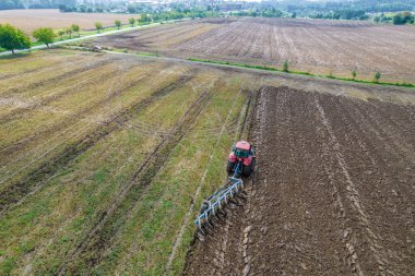 Toprağı bir traktörle sürüyorlar, üzerine saban bağlanmış, hava manzaralı. Tarım üretimi.