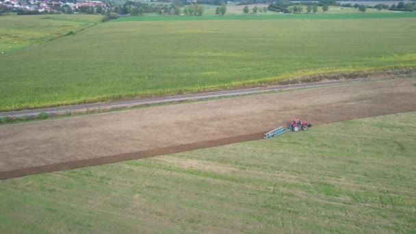 Il campo è arato da un trattore vicino alla ferrovia. Semina letame verde in un campo vicino al villaggio. — Video Stock