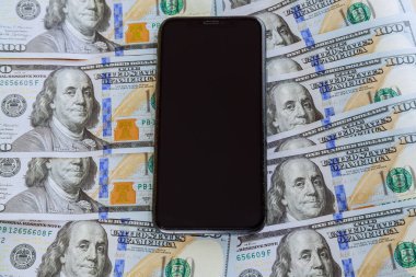 Dolarların arka planında cep telefonu. Döviz kurunun çözümü. Dolar alıp satmak..