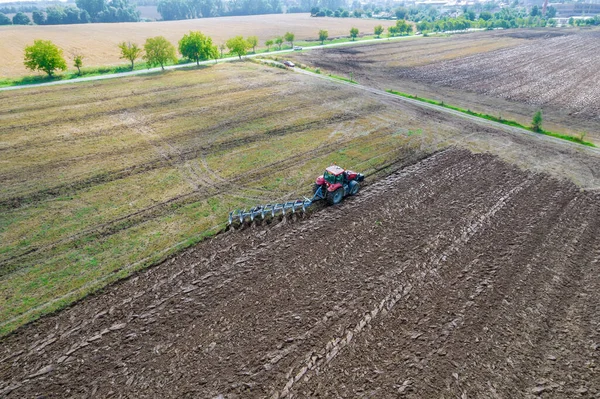 Ploužení země s traktorem, k němuž je připevněn pluh, letecký výhled. Zemědělská výroba — Stock fotografie