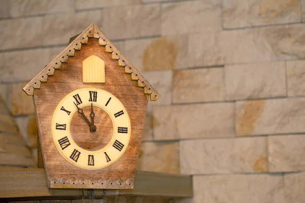 Годинник для зозулі прикрашає кам'яну стіну. Його майже дванадцята година на годиннику . — стокове фото