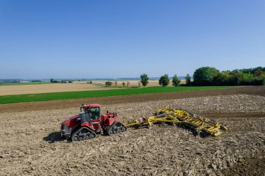 Büyük bir traktörle çiftliği harap ediyor. Toprak ekme hazırlığı. Yukarıdan görüntüle.
