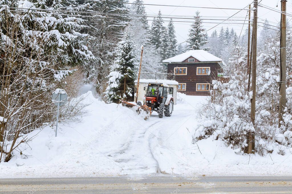 Snowplow for cleaning snow, removes snow on the road near houses.