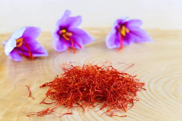 Saffron crocuses and dry saffron stamens on a wooden table. — Fotografia de Stock