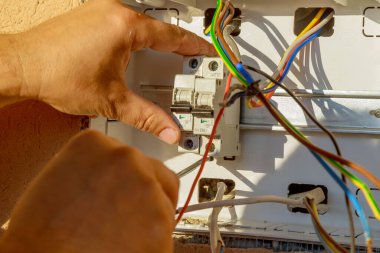 Elektrikli teçhizatlı panel. Bir elektrikçi devre kesici takıyor. Elle kumandalı aygıtlar, küçük yük akımlarının bağlantısını kesmek üzere tasarlanmıştır..