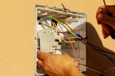Elektrikli teçhizatlı panel. Bir elektrikçi devre kesici takıyor. Elle kumandalı aygıtlar, küçük yük akımlarının bağlantısını kesmek üzere tasarlanmıştır..