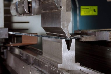 Metal levha parçalarını bükme makinesi kullanarak bükmek. Metal parçalarının üretimi.