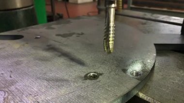 Musluk delikteki bir ipliği kesiyor. Sondaj ve iplik için profesyonel bir araç. Metal Çalışması.