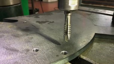 Musluk delikteki bir ipliği kesiyor. Sondaj ve iplik için profesyonel bir araç. Metal Çalışması.