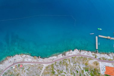 Mavi Adriyatik Denizi 'nin üst manzarası, denizdeki katamaranlar. Deniz kenarındaki taş plajda yürüme yolu var...