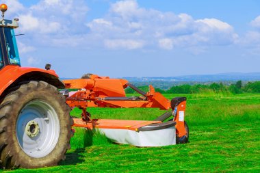 Kırmızı büyük çim biçme makinesi tarladaki çimleri biçer. Kış için ekin hazırlığı. Haymaking.