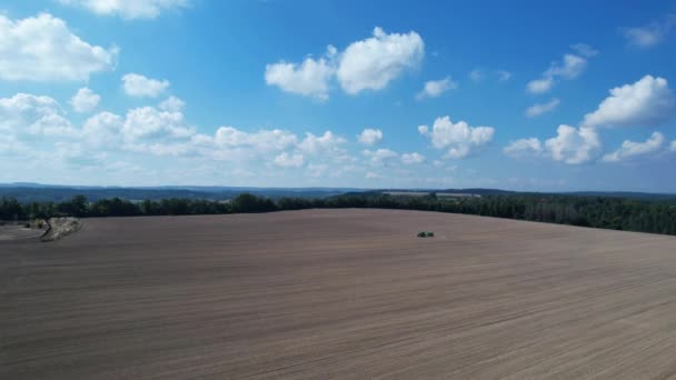 Tractor Atraviesa Campo Rociando Campo Sembrado Cerca Bosque Contra Cielo — Vídeos de Stock