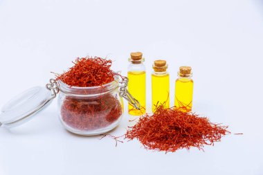 Glass jar filled with red saffron stamens and pile of red stamens. And saffron drink on a white background. Expensive spice.